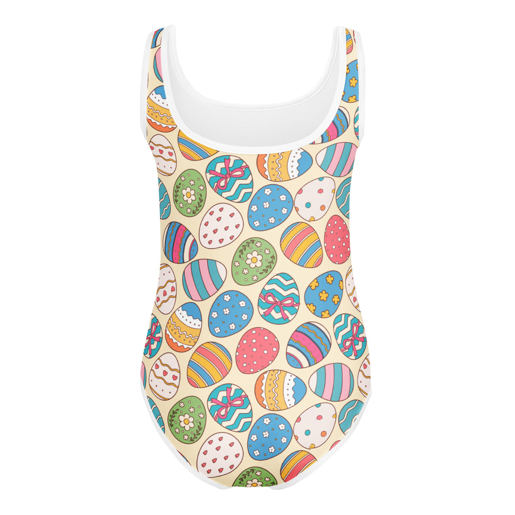 A beige buttery soft one-piece swimsuit with white trim and colorful cartoon easter egg patterns for girls dance and gymnastics