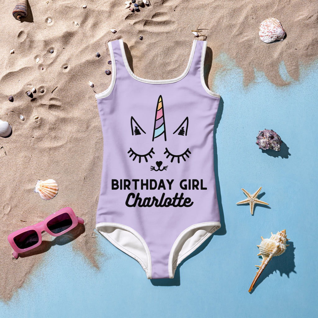 Lavender one-piece swimsuit with white trim featuring a rainbow unicorn face and birthday girl Charlotte print