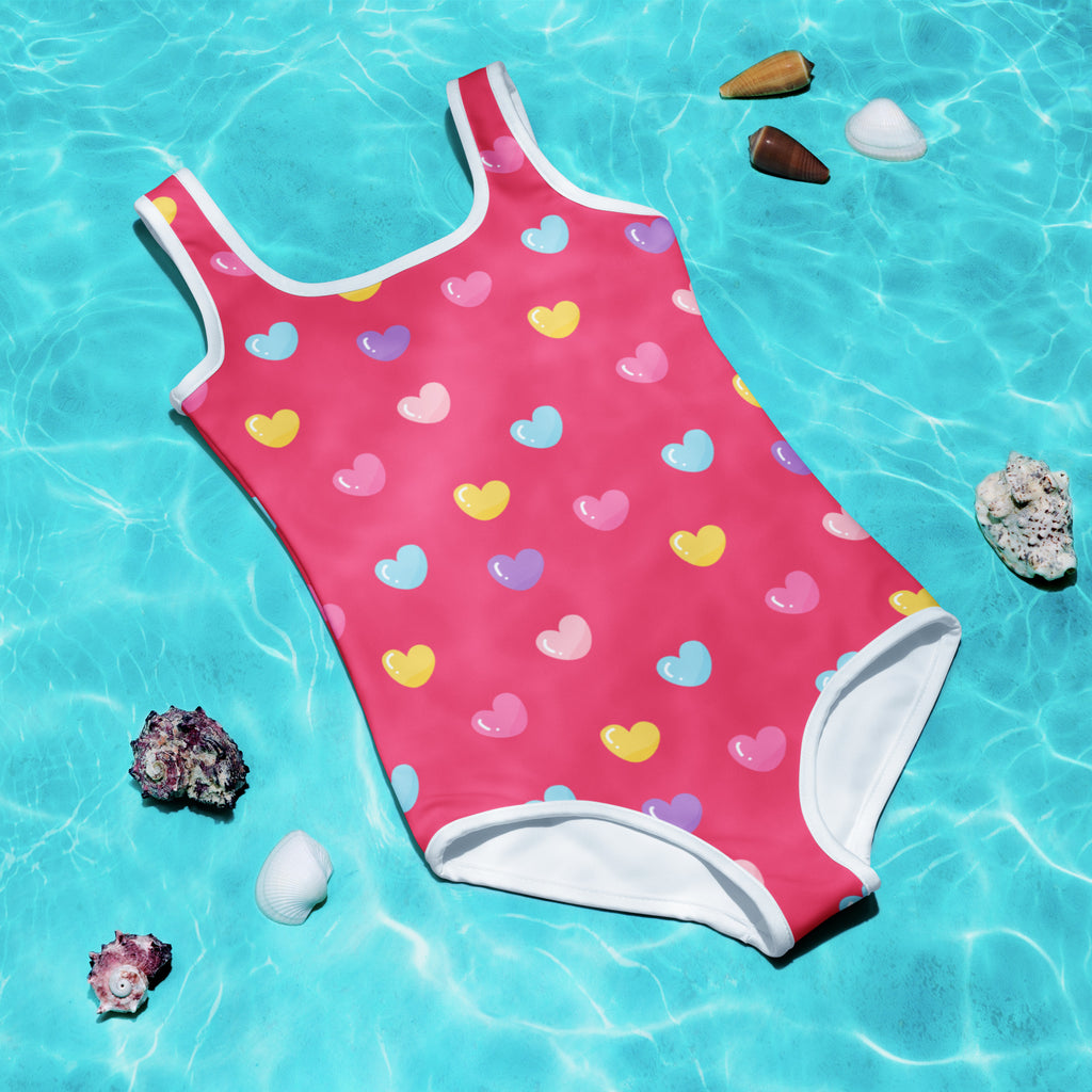A girls colorful hearts pink buttery soft swimsuit with upf 50 featuring multicolored heart pattern and white trim