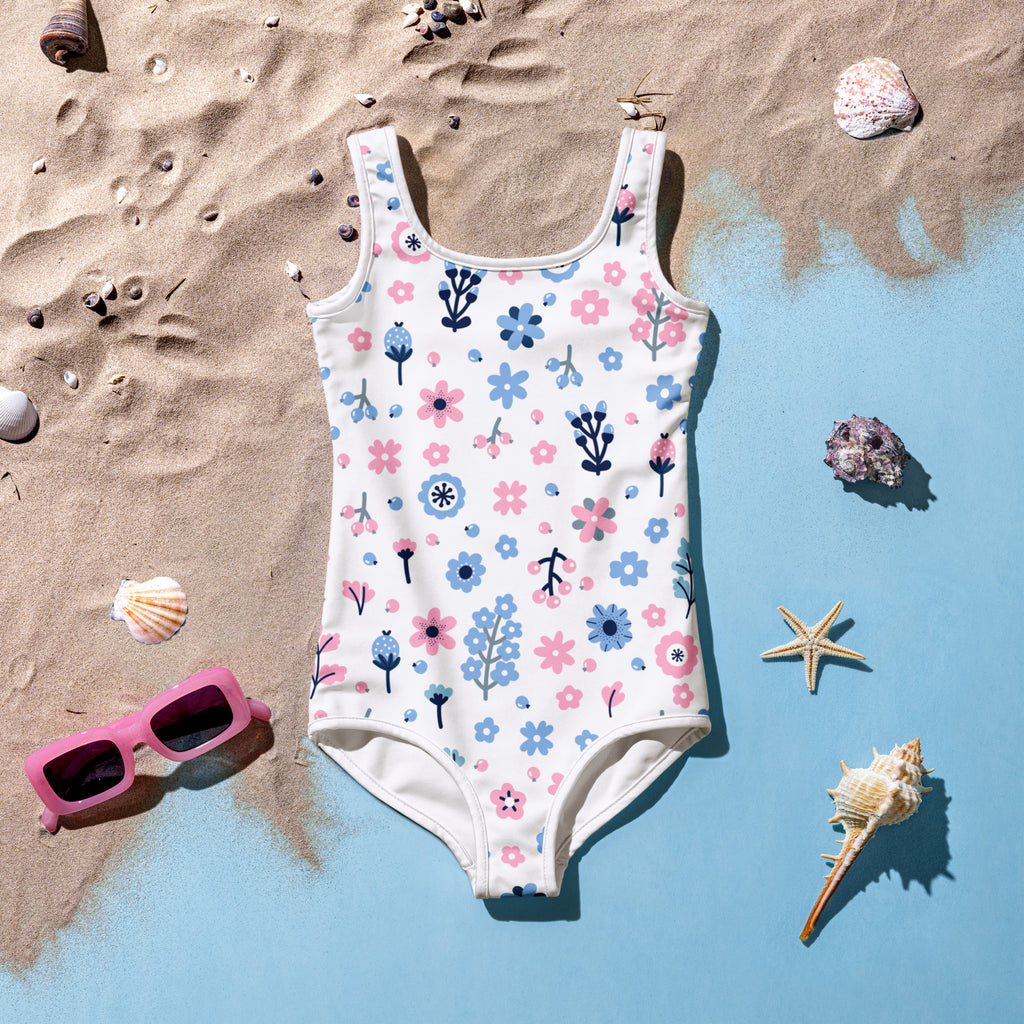 White one-piece girls swimsuit with pink and blue floral pattern buttery soft fabric and upf 50 plus protection on beach decor