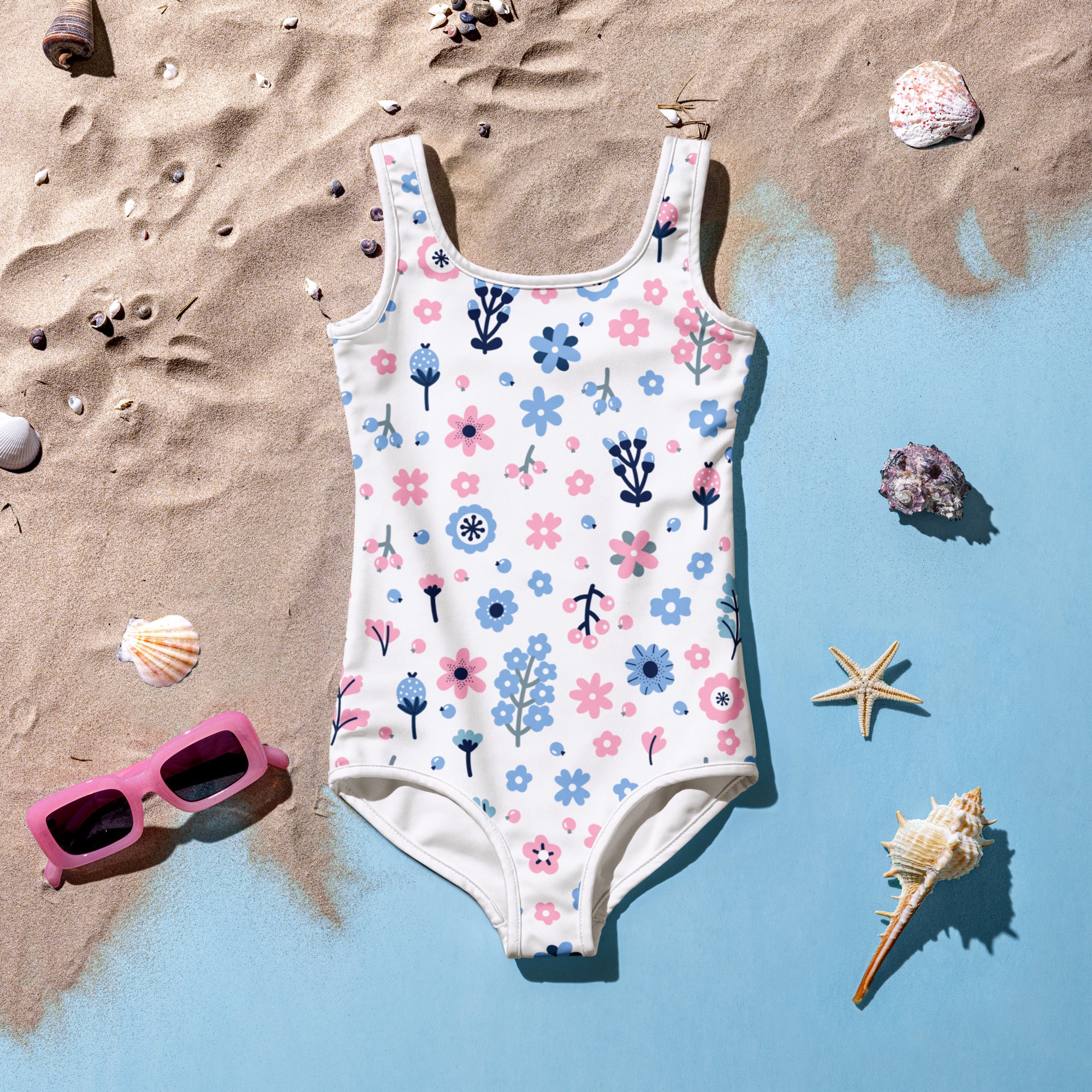 White one-piece girls swimsuit with pink and blue floral pattern buttery soft fabric and upf 50 plus protection on beach decor