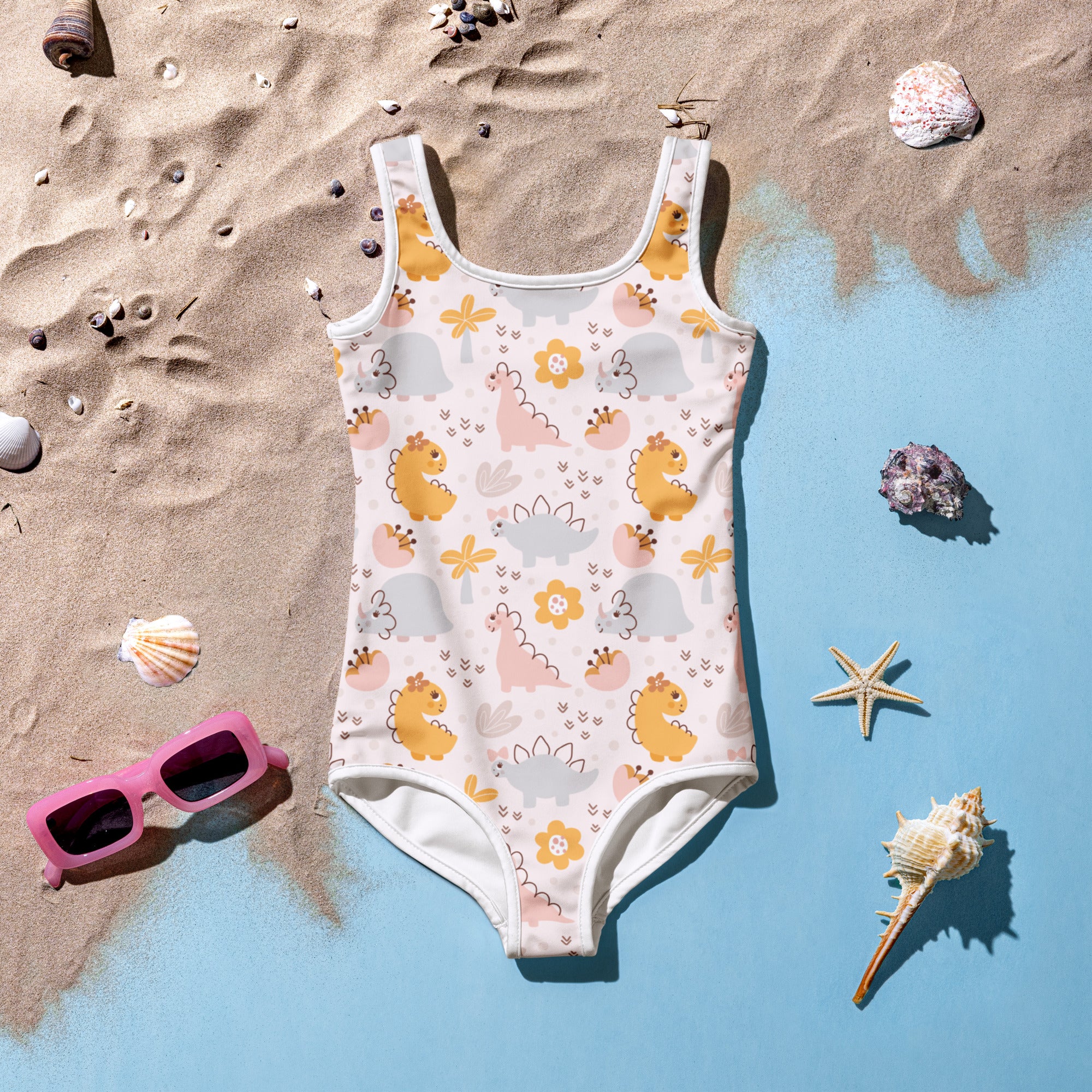A playful off-white girls one-piece swimsuit with yellow and pink dinosaur print and orange flowers with UPF 50+ protection