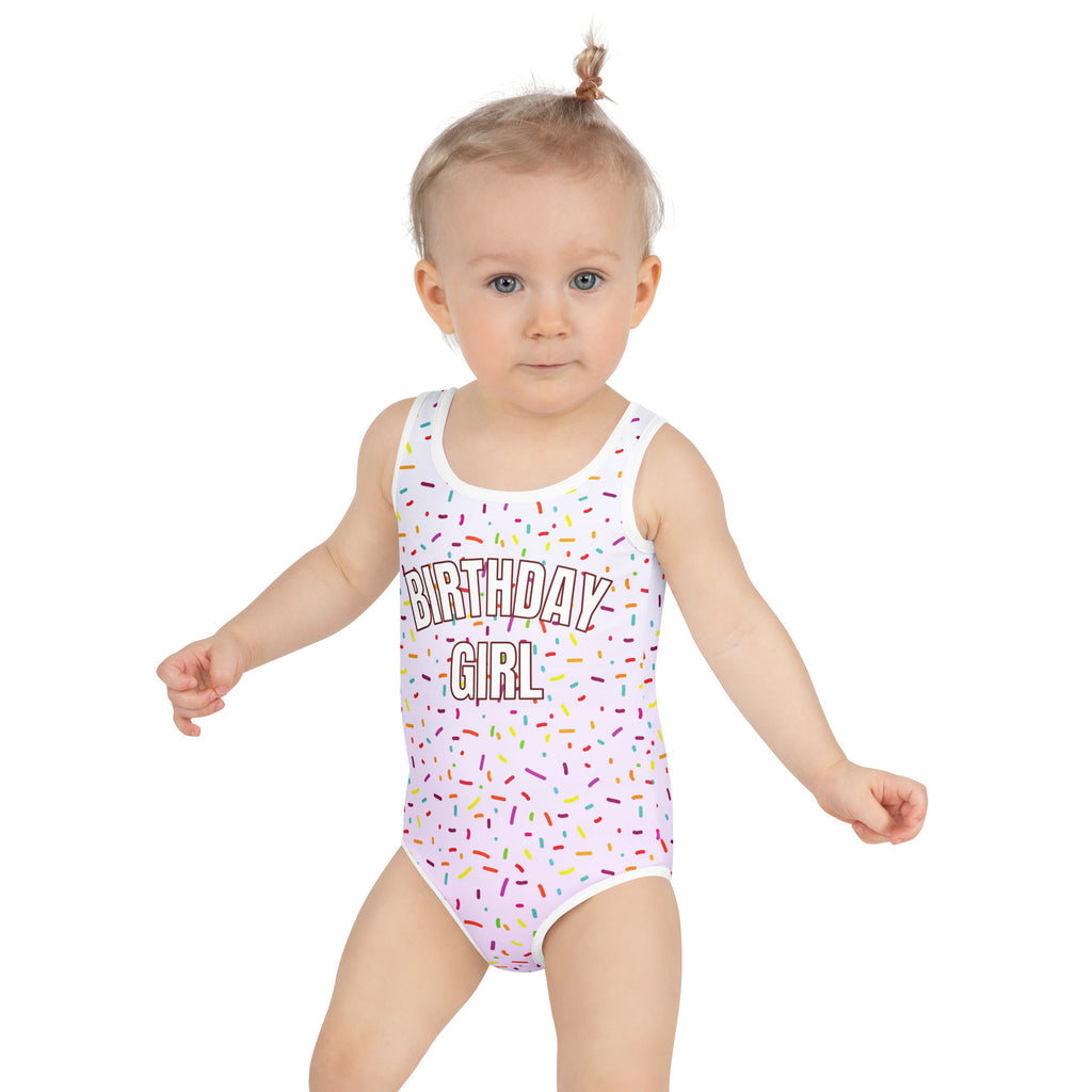 White one-piece swimsuit with colorful sprinkle pattern and birthday girl text made of buttery soft fabric with UPF 50+