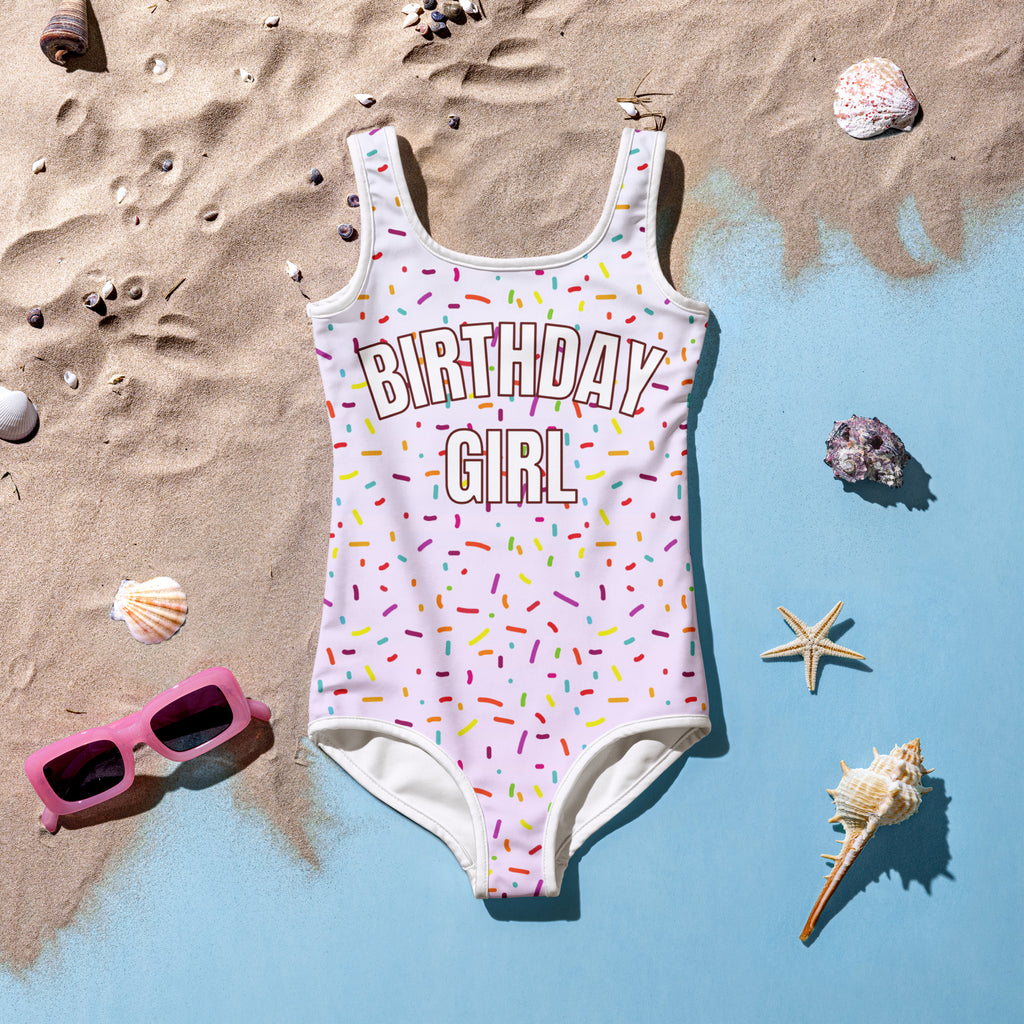 White buttery soft one-piece birthday girl swimsuit with colorful outlined letters and rainbow sprinkle pattern upf 50+