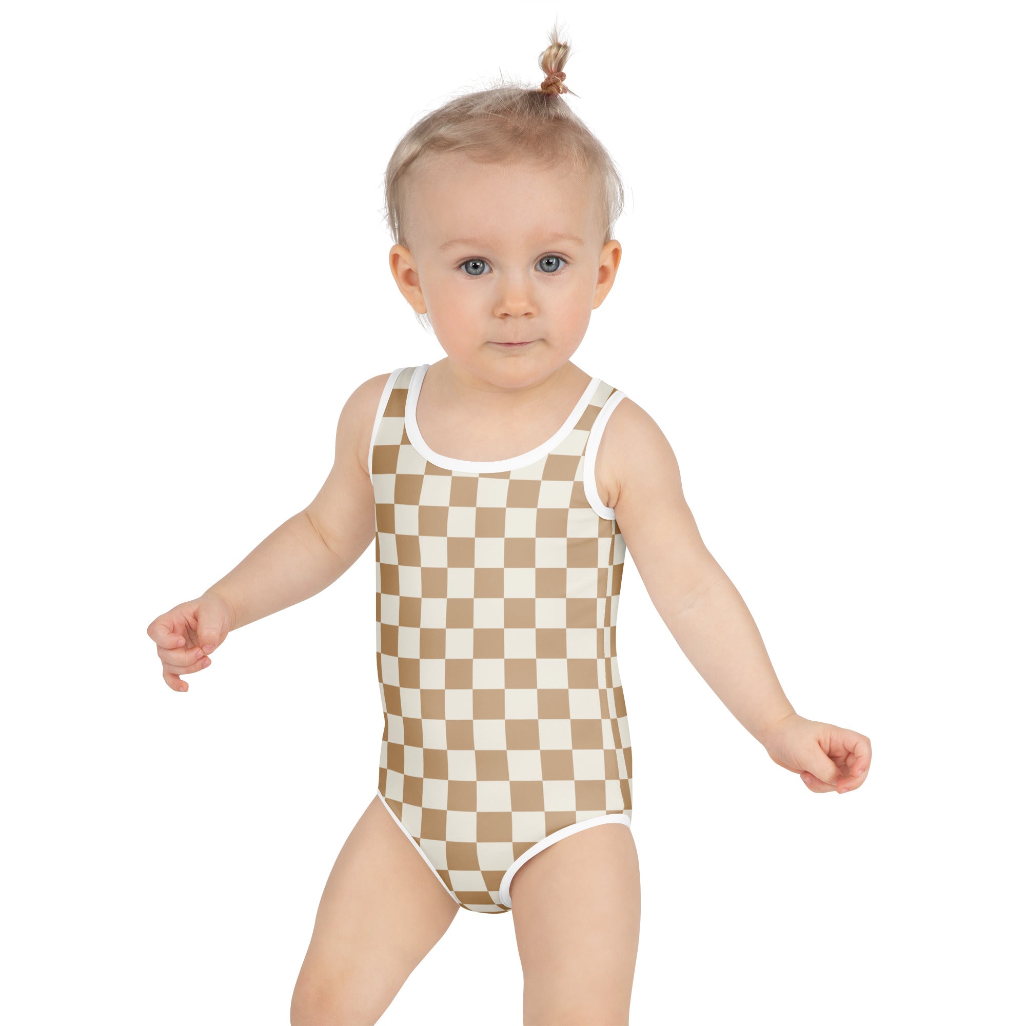 A toddler wearing a beige and white checkered girls sand checkerboard buttery soft swimsuit with UPF 50+ white trim