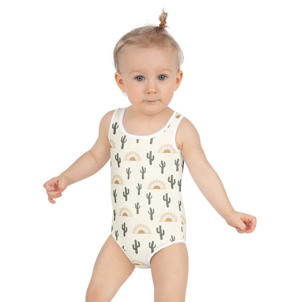 Girls cactus desert sunrise buttery soft white one-piece swimsuit with black cacti and gold sun motifs and UPF 50+ protection