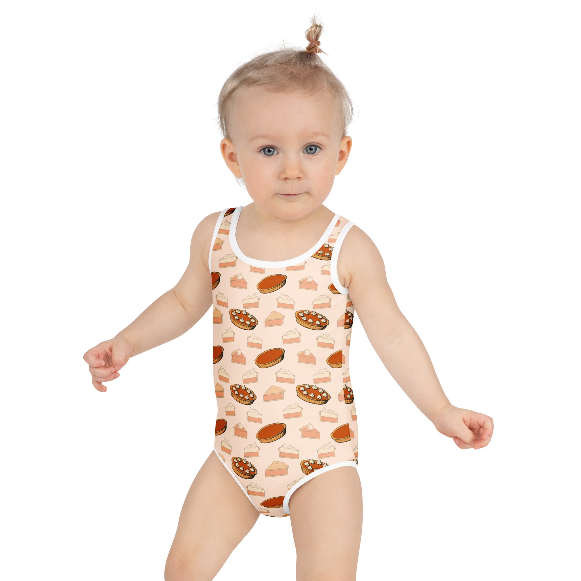 A toddler wearing a girls pumpkin pie thanksgiving buttery soft beige swimsuit with pie slice pattern and UPF 50+ protection