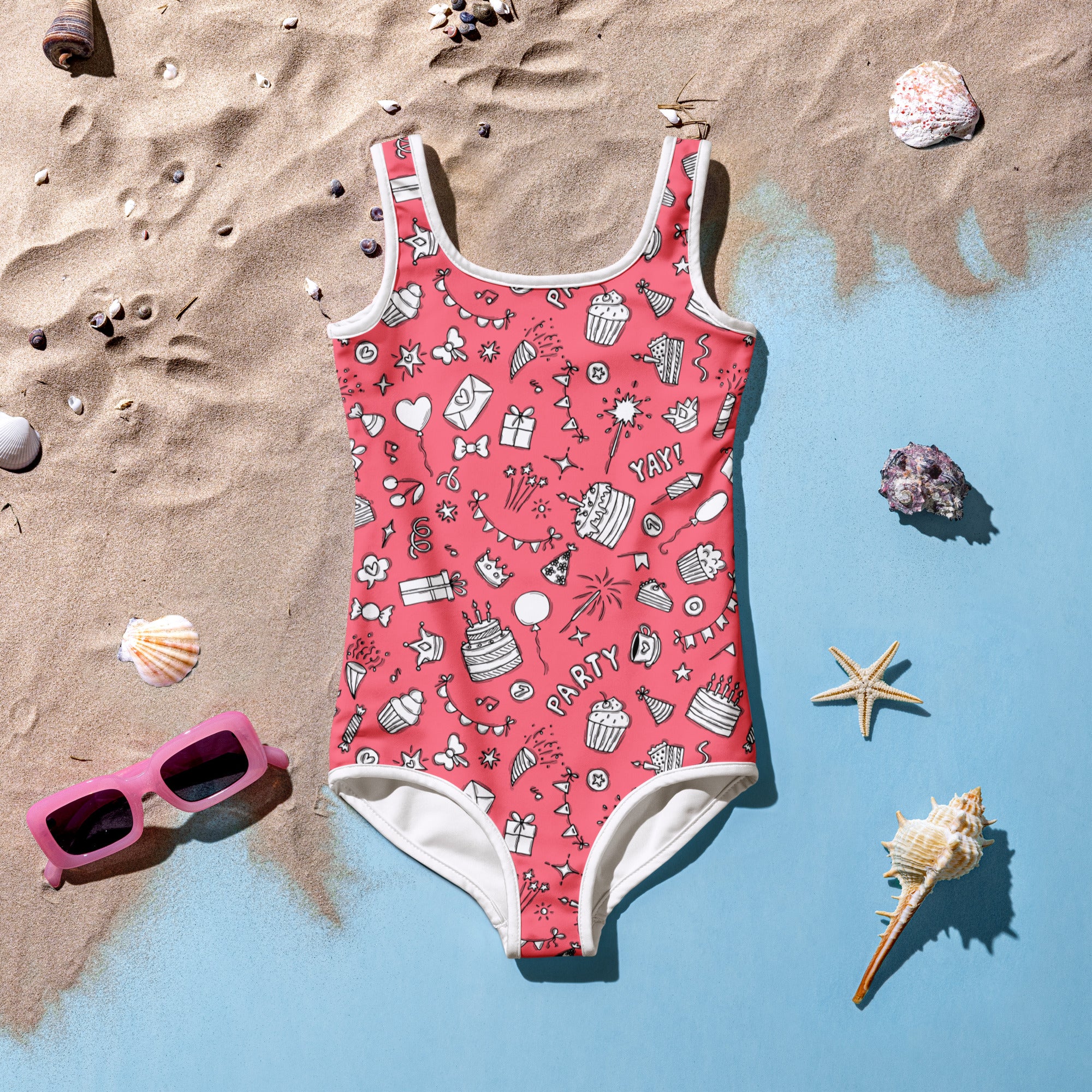 Girls pink birthday party buttery soft swimsuit with upf 50 plus featuring white trim and festive cupcake and balloon prints on sand
