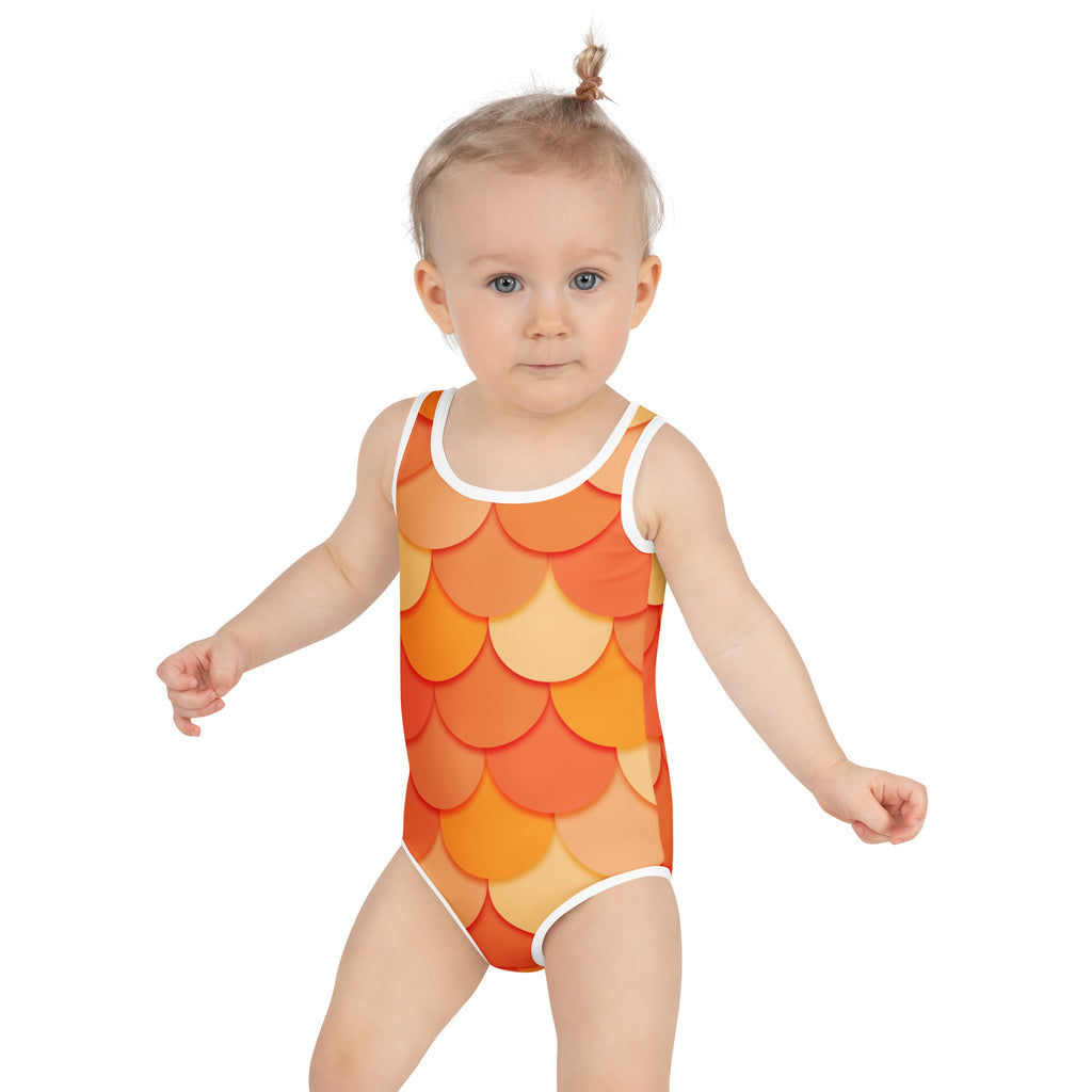 A toddler wears a girls orange mermaid buttery soft one-piece swimsuit with fish-scale pattern and UPF 50 plus protection