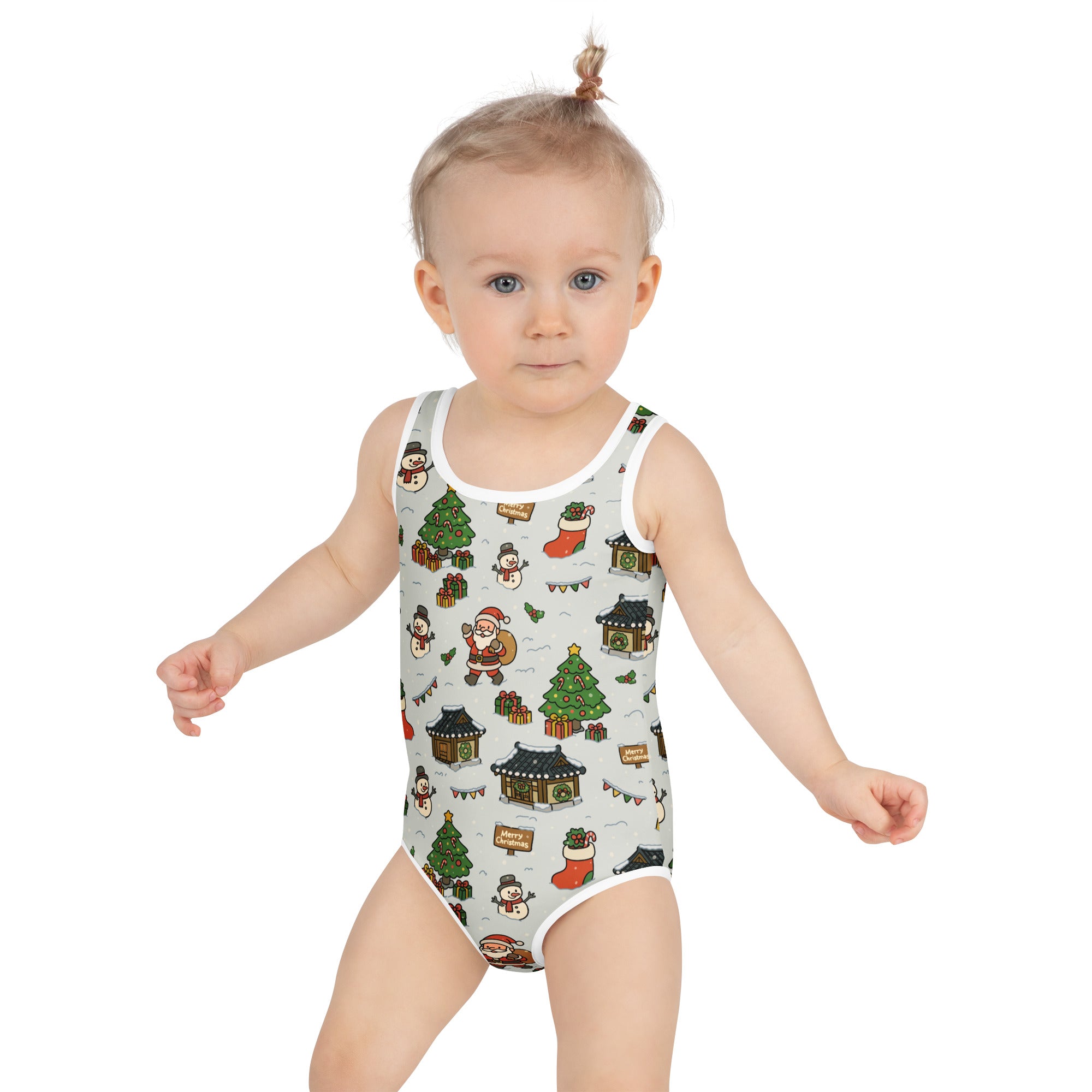 A child wearing a girls santa and christmas village buttery soft swimsuit with UPF 50 plus on light gray background