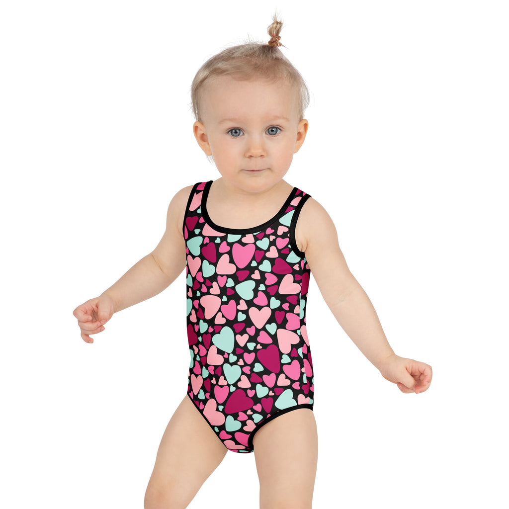 A child wearing a black girls Valentine’s Day heart buttery soft swimsuit with UPF 50+ and double layered front