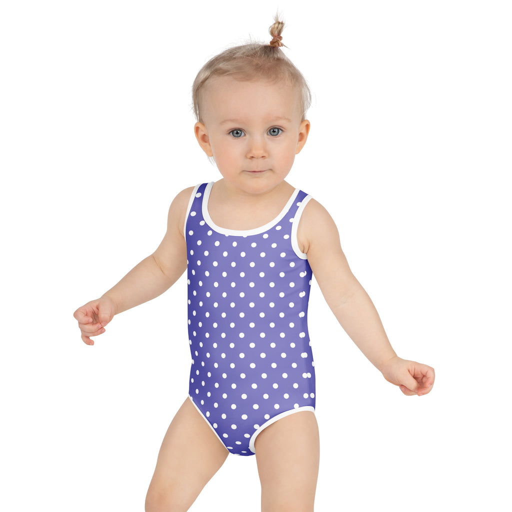 A child wearing a girls purple polka dot buttery soft swimsuit with white trim and UPF 50 plus protection