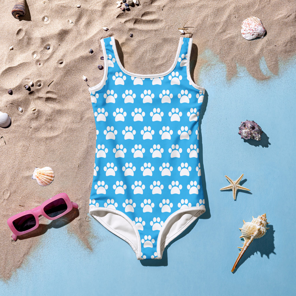 A bright blue girls one-piece swimsuit with white paw prints and trim made of buttery soft fabric with UPF 50 plus