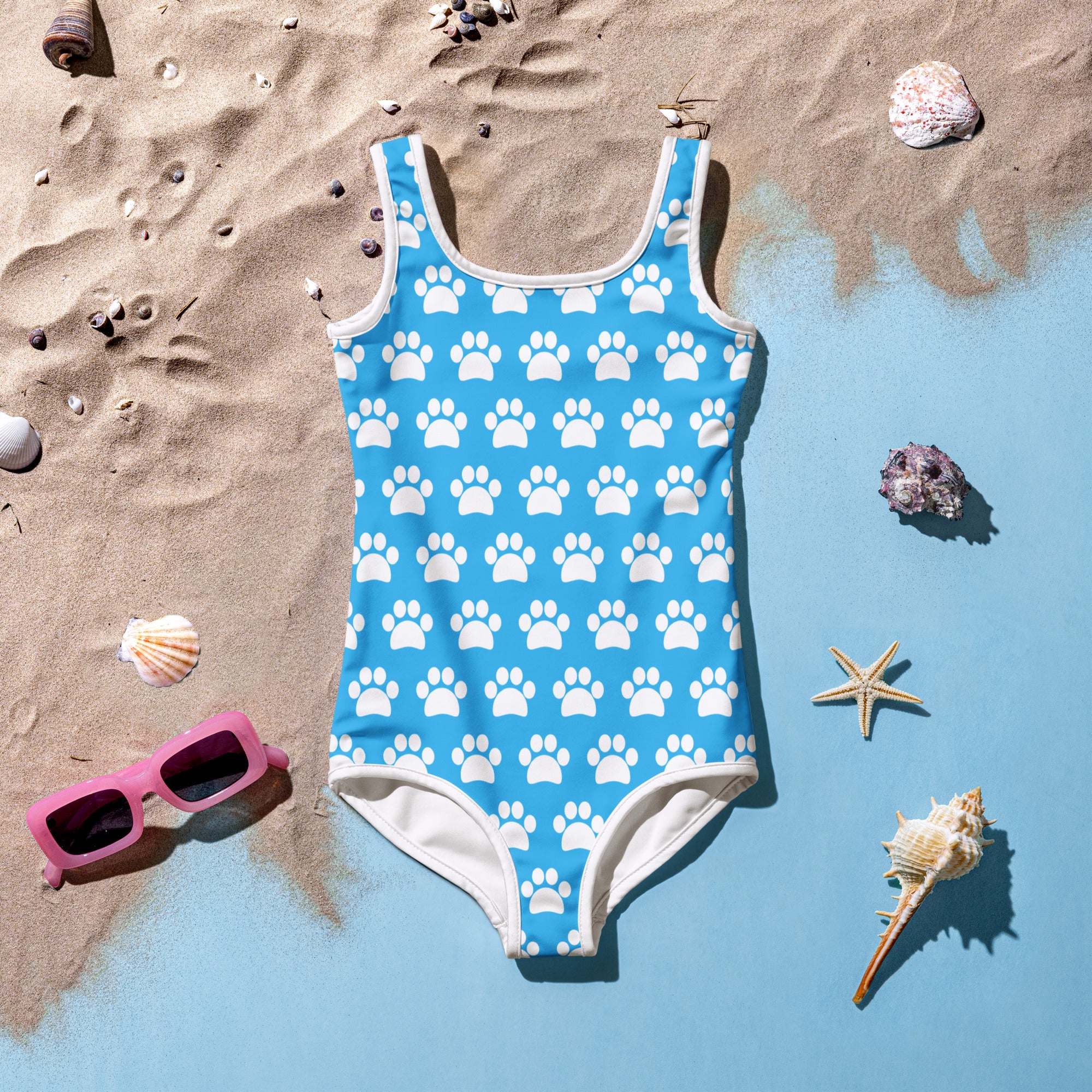 A bright blue girls one-piece swimsuit with white paw prints and trim made of buttery soft fabric with UPF 50 plus