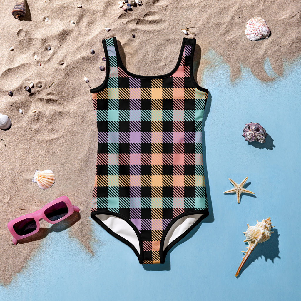 Plaid swimsuit on a sandy surface with shells and sunglasses