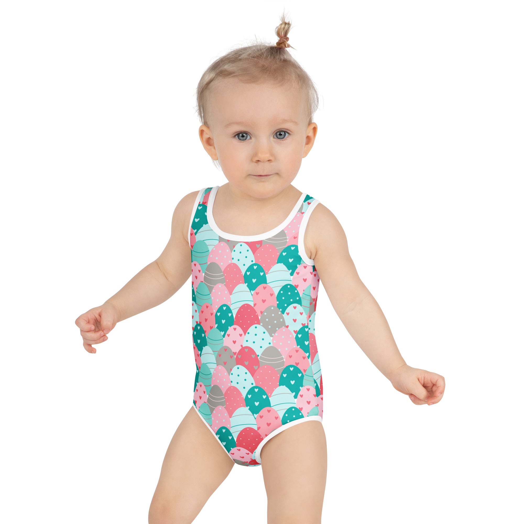 A girl wearing a buttery soft girls Easter eggs swimsuit with colorful heart-dotted egg patterns and UPF 50 plus protection