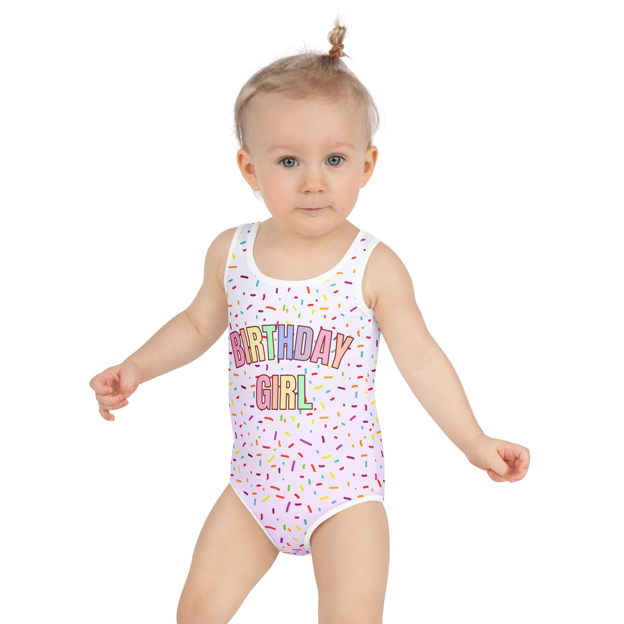 Child wearing a 'Birthday Girl' swimsuit with colorful text and sprinkles on a white background