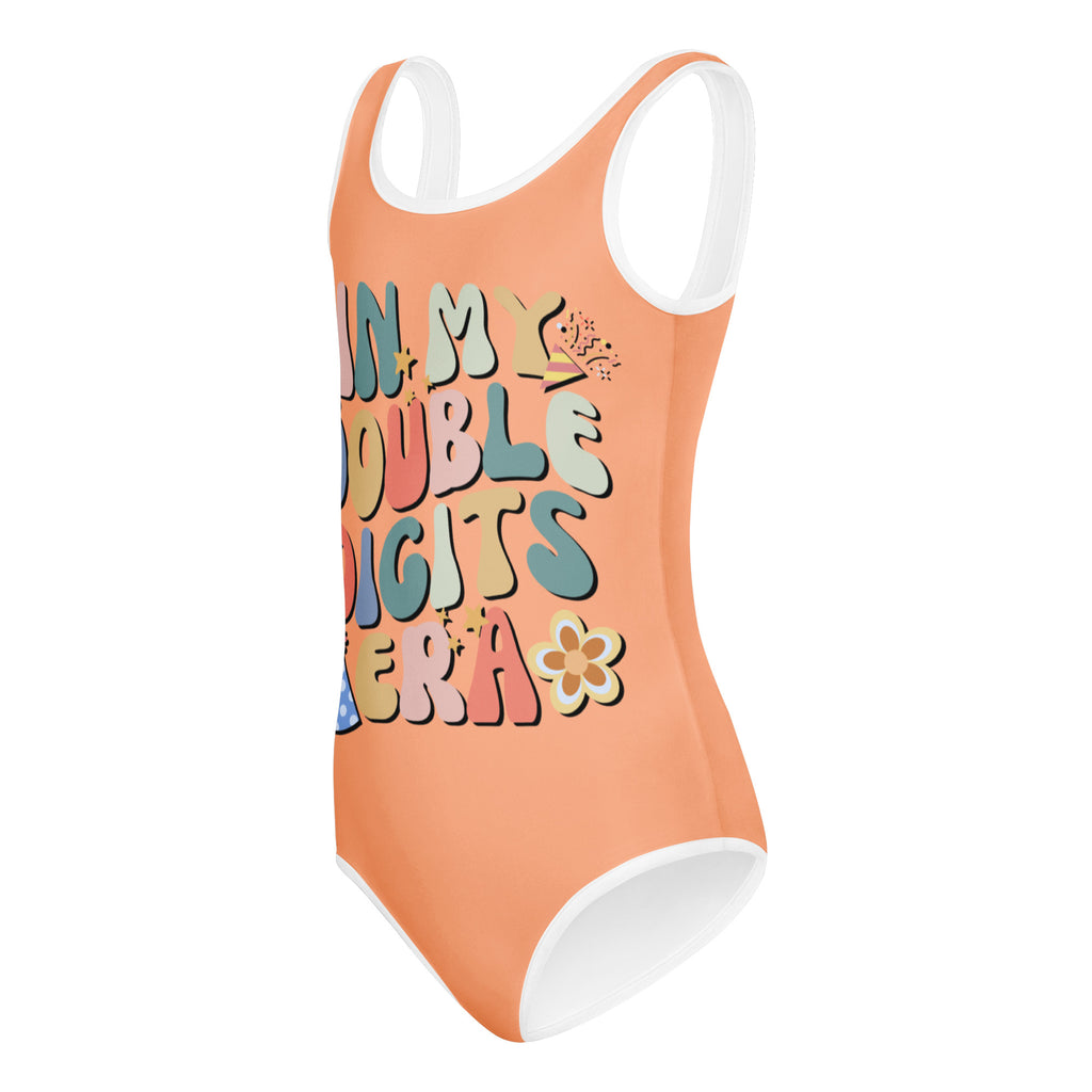 A vibrant peach girls buttery soft quick drying one-piece swimsuit with white trim and double digits era graphic design