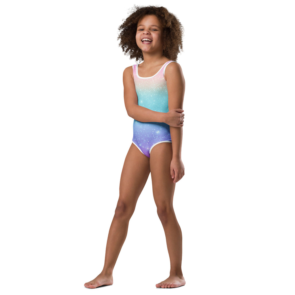 A girl wearing a girls faux sparkle effect rainbow buttery soft leotard with a pink to blue purple galaxy print for dance