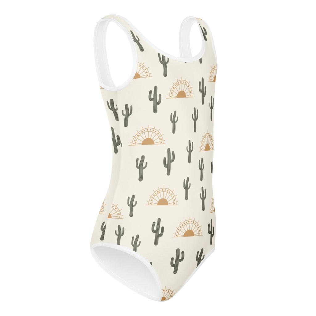 Cream-colored girls cactus desert sunrise buttery soft one-piece swimsuit with black cacti and gold sun motifs for dance