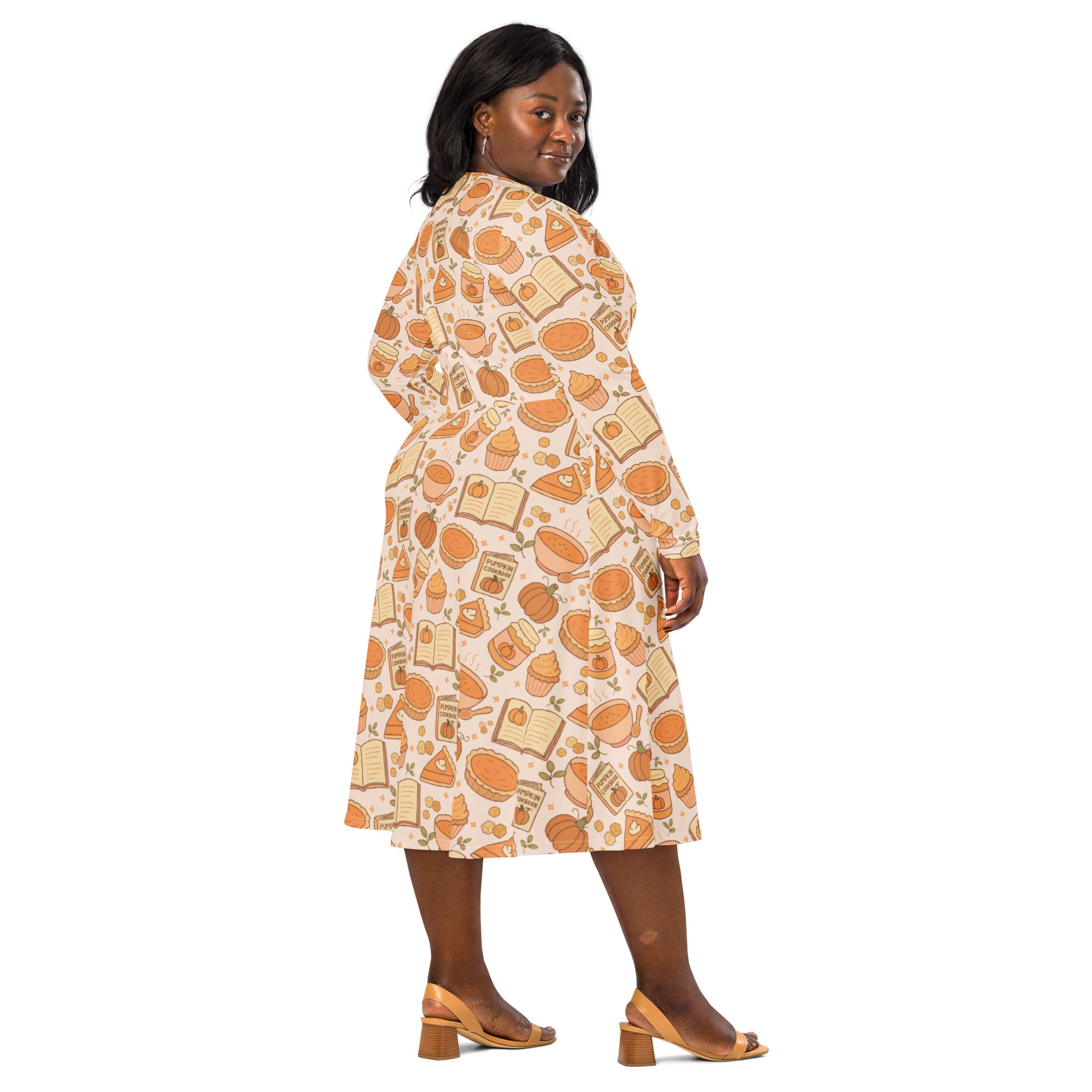 A plus-size woman wears a pumpkin pie themed long sleeve midi dress with pockets in cream with orange and beige prints