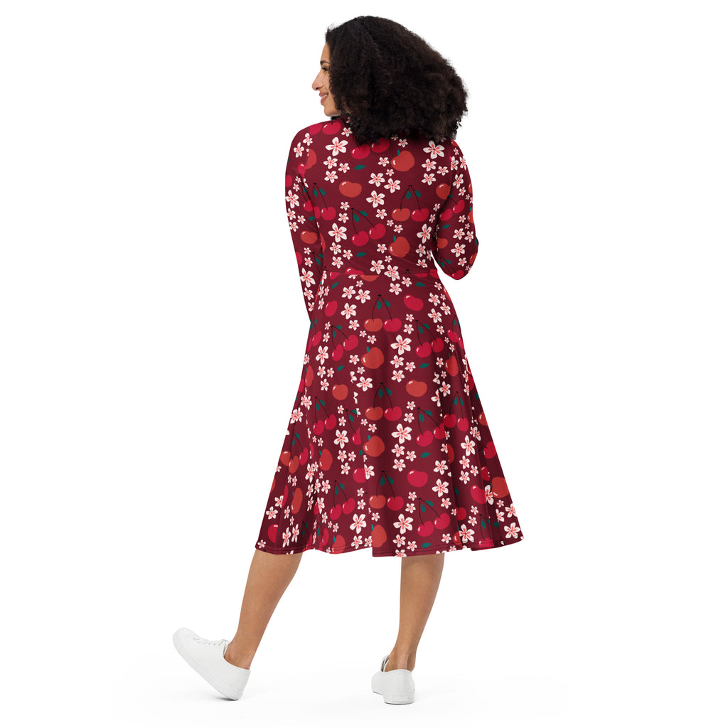 A woman wears a maroon cherry blossom long sleeve midi wrap dress with pockets featuring pink flowers and red cherries