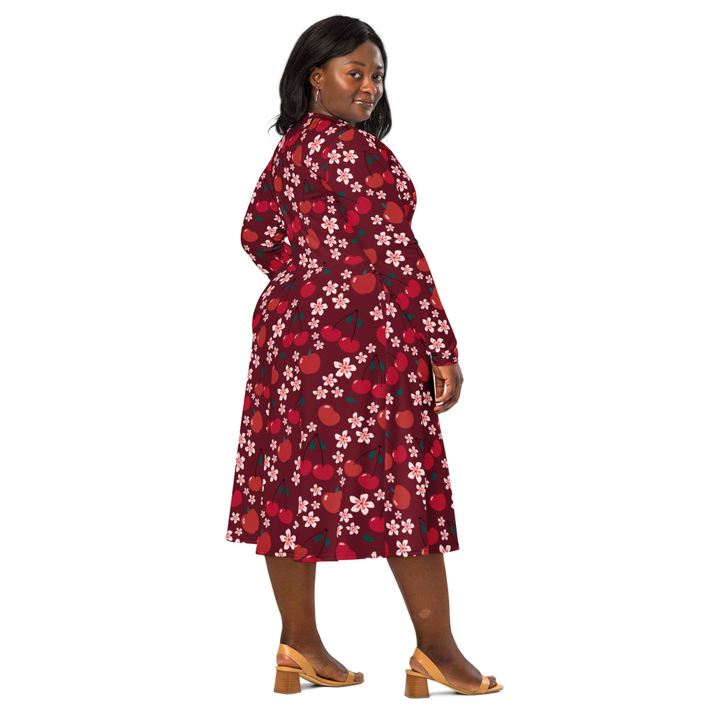 A plus-size woman wears a maroon long sleeve midi dress with cherry and pink blossom pattern and pockets