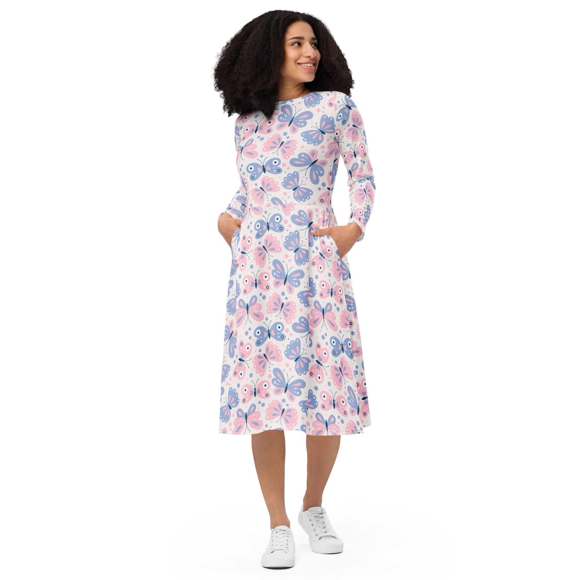 A woman wearing a white long sleeve midi dress with pink and purple butterfly pattern and pockets