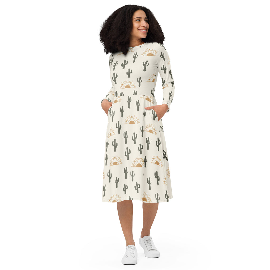Women’s off-white midi dress with black cactus and gold sun print, long sleeves, and side pockets