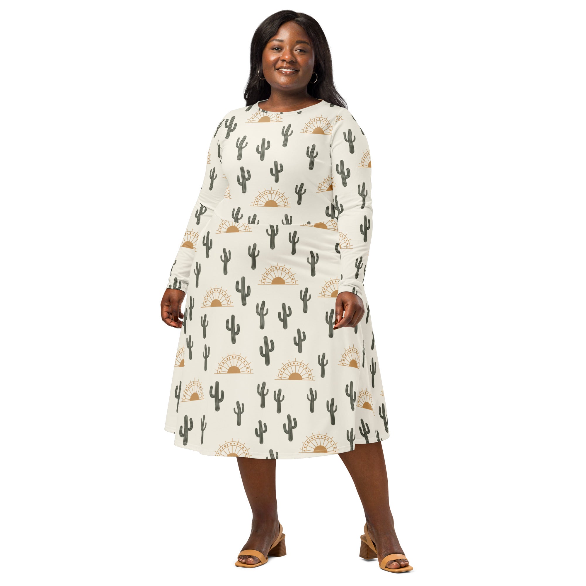 A plus-size woman wears a cream long sleeve a-line midi dress with black cactus and gold sunburst patterns with pockets