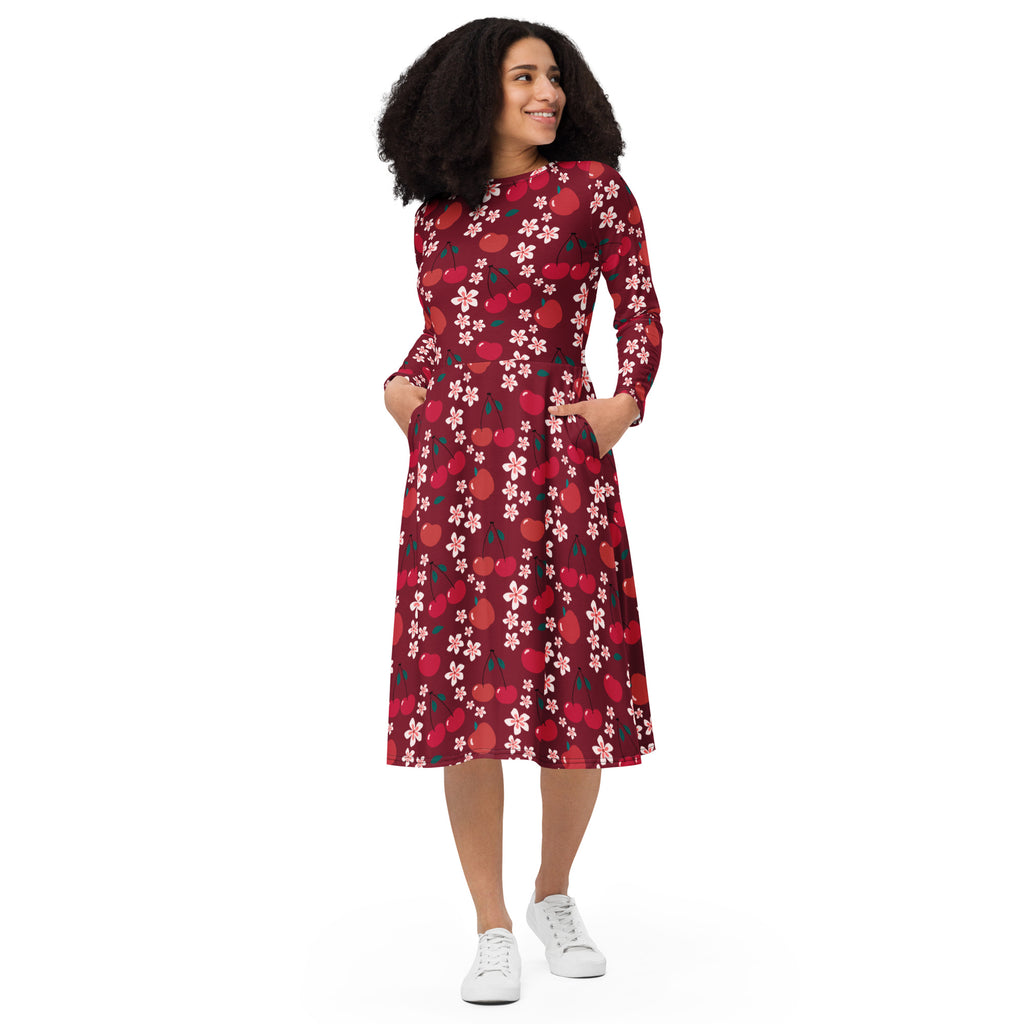 A woman wears a maroon long sleeve midi dress with cherry and blossom pattern featuring pockets