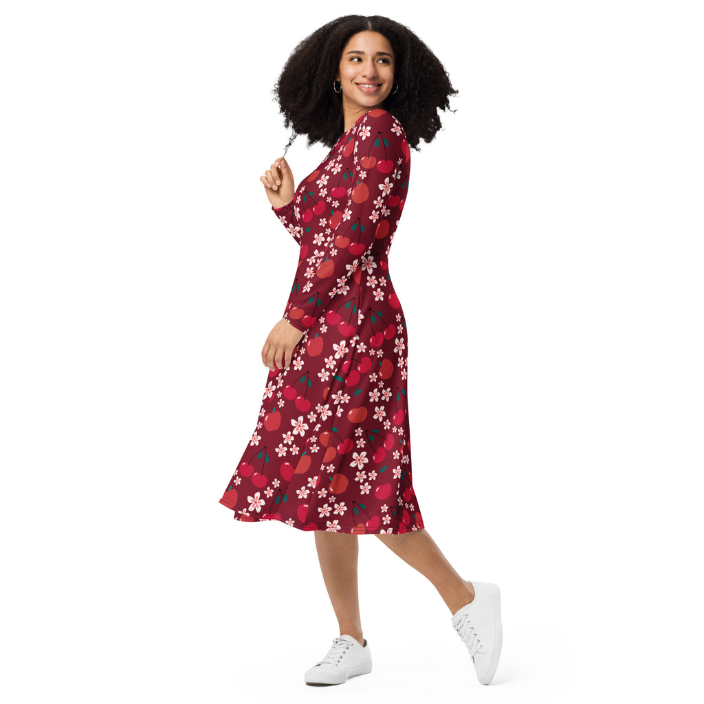 A woman wearing a vibrant red cherry blossom long sleeve midi dress with pockets and pink floral patterns