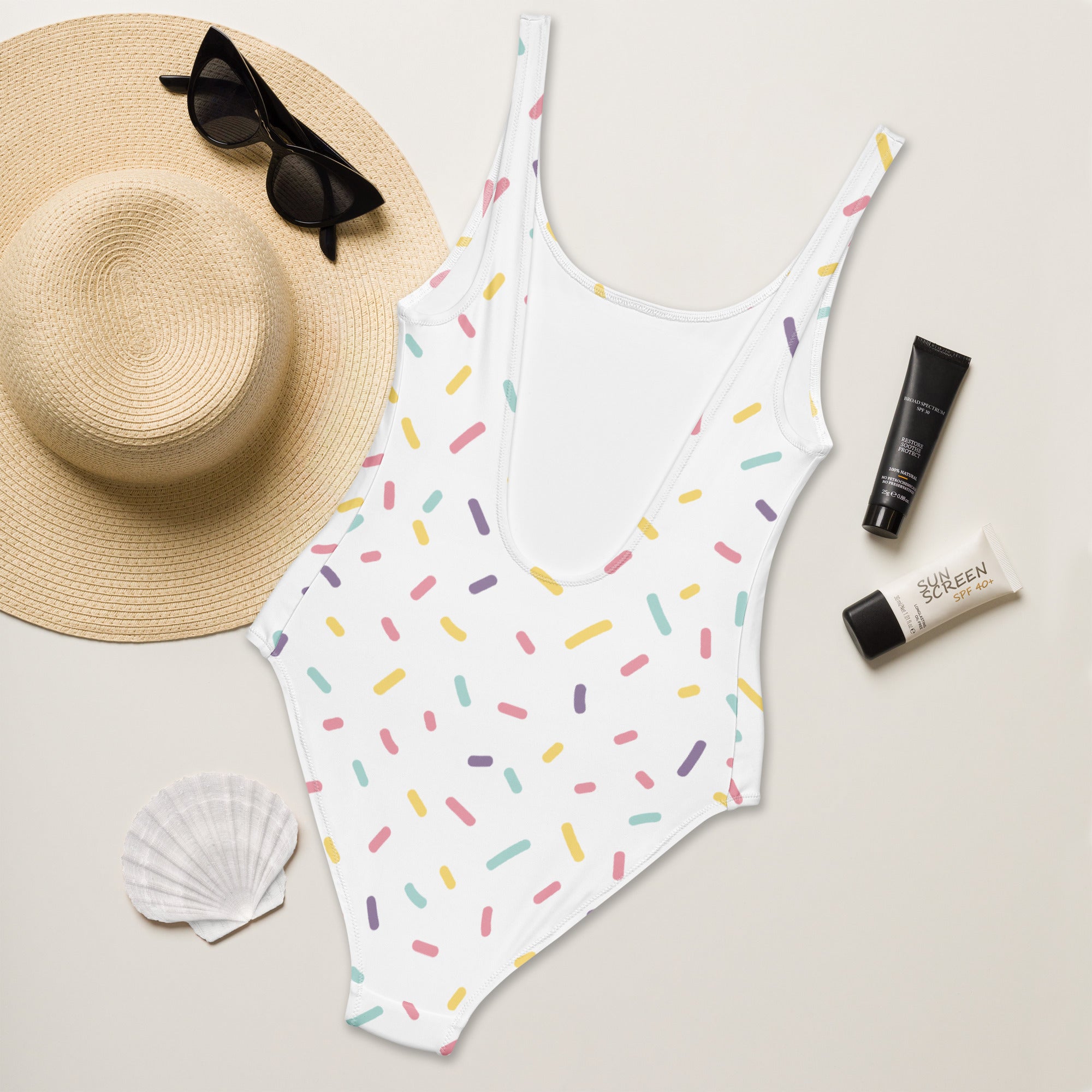 A white one-piece womens swimsuit with colorful pastel sprinkles made of buttery soft fabric with UPF 50 plus protection