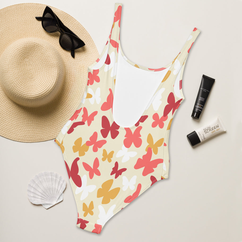 A vibrant women’s warm-tone one-piece swimsuit with red pink yellow white butterfly pattern on off-white buttery soft fabric with UPF 50+