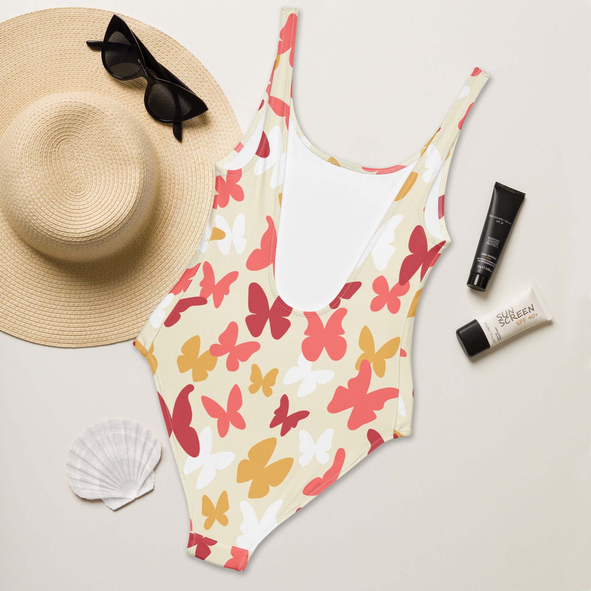 A vibrant women’s warm-tone one-piece swimsuit with red pink yellow white butterfly pattern on off-white buttery soft fabric with UPF 50+
