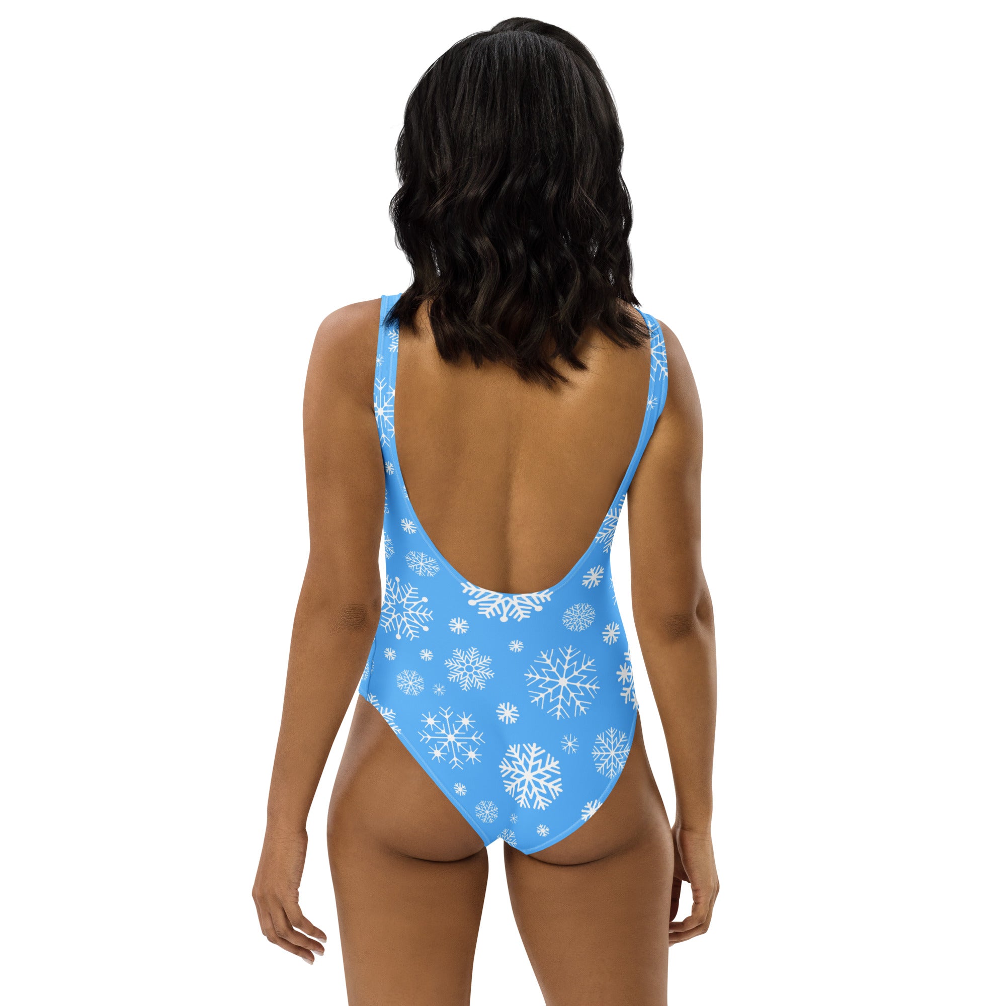 Back view of a women’s light blue buttery soft one-piece swimsuit with white snowflake patterns and upf 50+ protection
