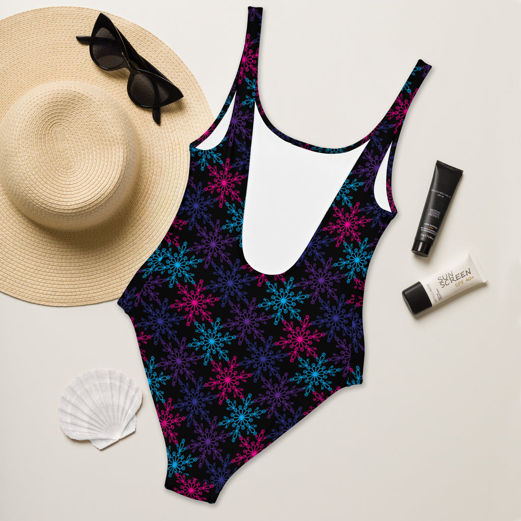 A vibrant black one-piece neon snowflake swimsuit with pink blue and purple patterns and buttery soft fabric with UPF 50+