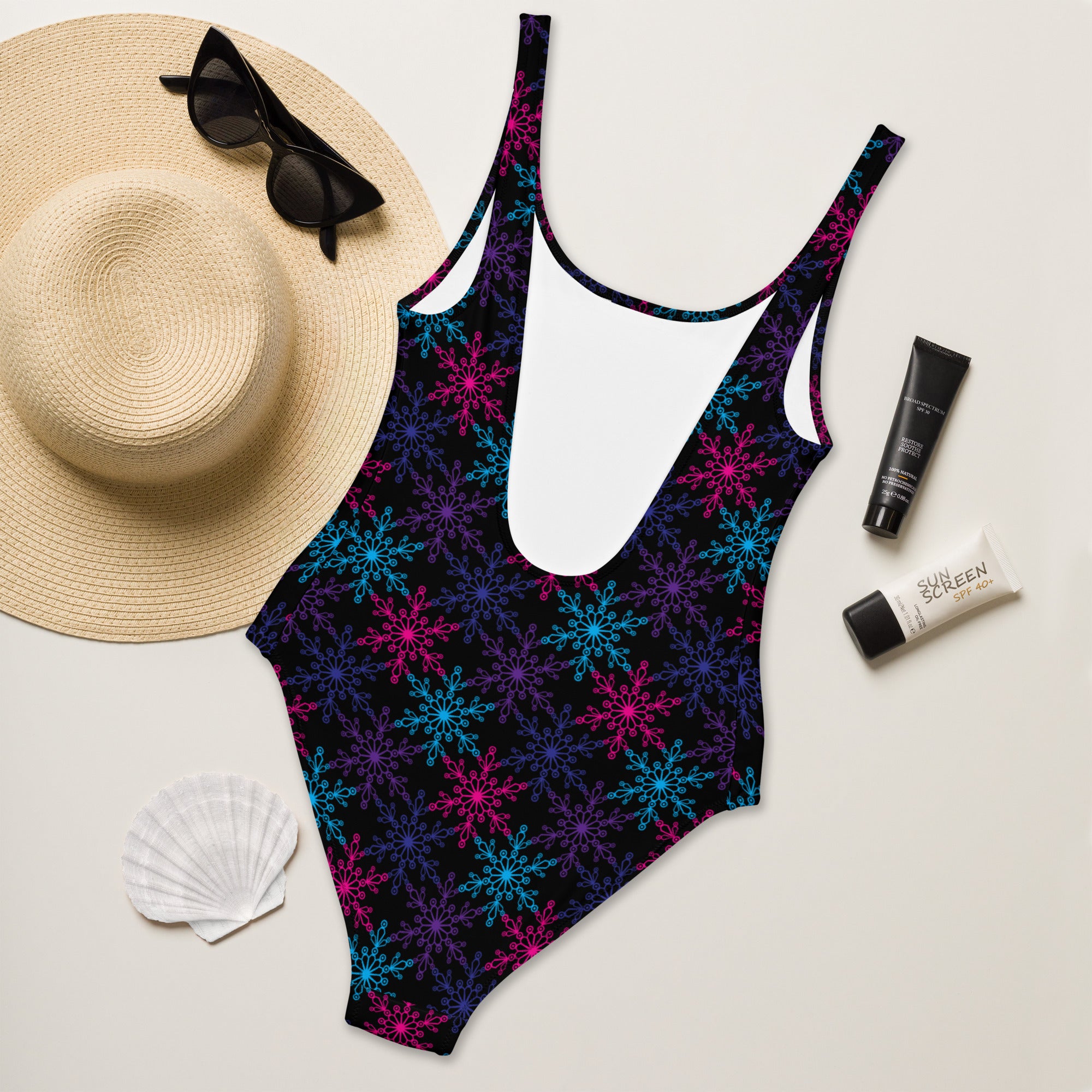 A vibrant black one-piece neon snowflake swimsuit with pink blue and purple patterns and buttery soft fabric with UPF 50+