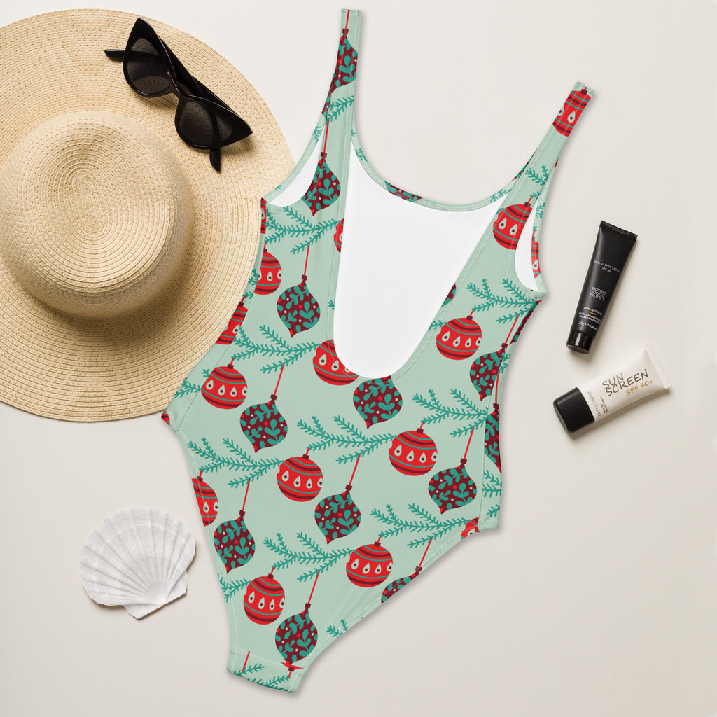 A mint green buttery soft one-piece swimsuit with festive red and teal Christmas ornaments and pine branches and UPF 50+