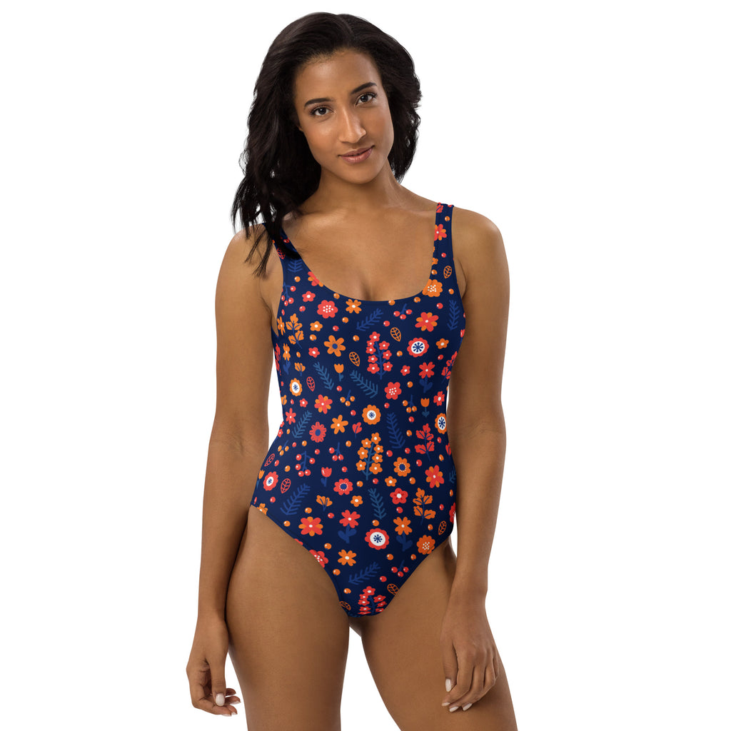 A navy blue women’s one-piece dark floral buttery soft swimsuit with vibrant orange red white flowers and UPF 50+ protection