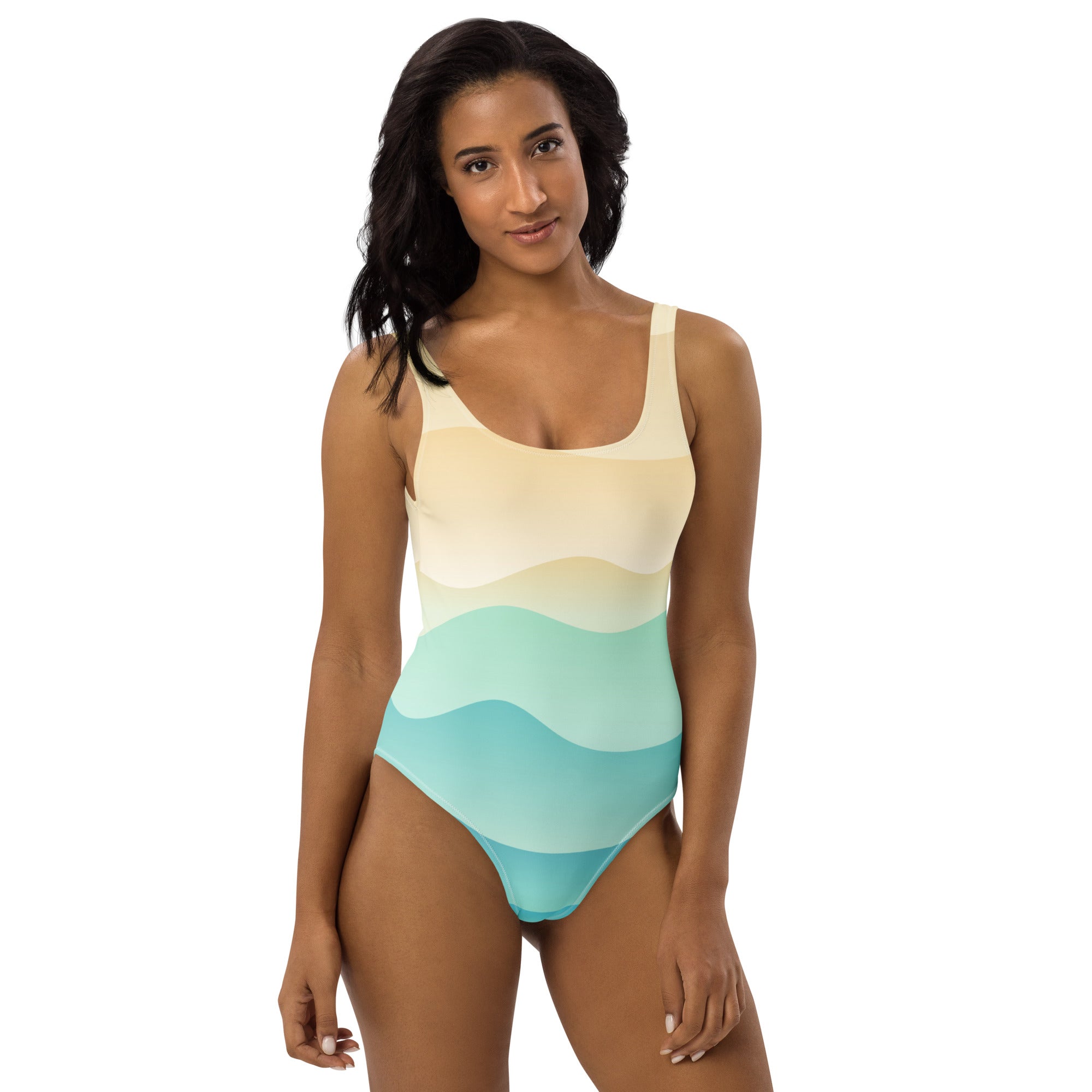 A woman wears a buttery soft women’s one-piece swimsuit with sandy ocean wave gradient in cream and blue hues with UPF 50+