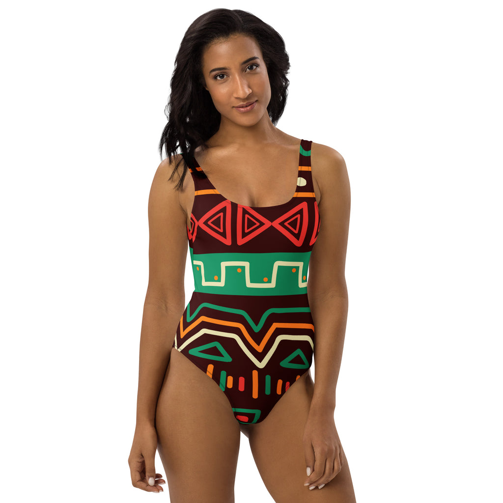 Women’s african-inspired tribal print one-piece swimsuit with bold geometric red green orange and cream on dark brown base