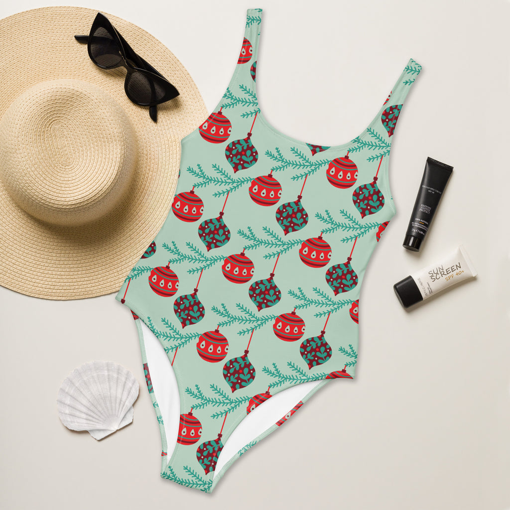 A mint green buttery soft one-piece swimsuit with red and teal christmas ornaments and holly leaves and UPF 50+ protection