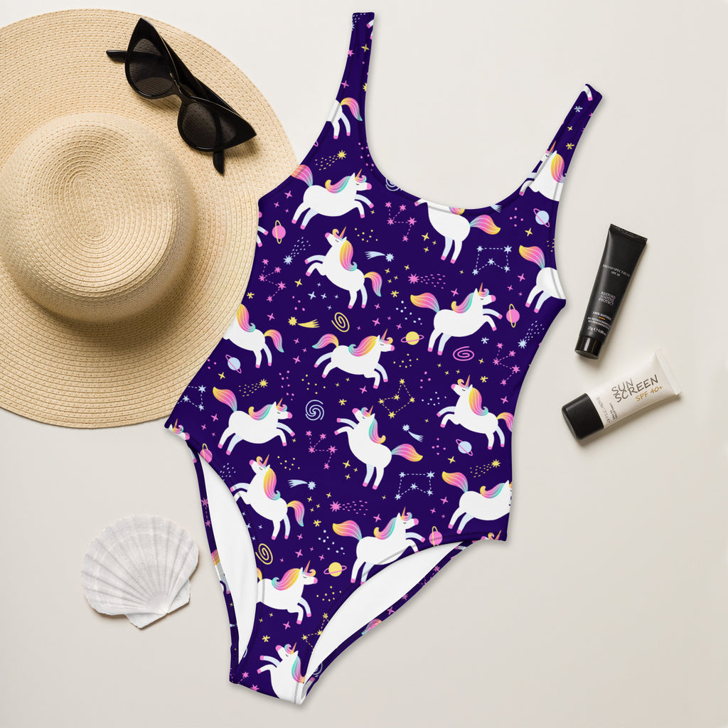 Purple swimsuit with unicorn pattern on a light surface with accessories.