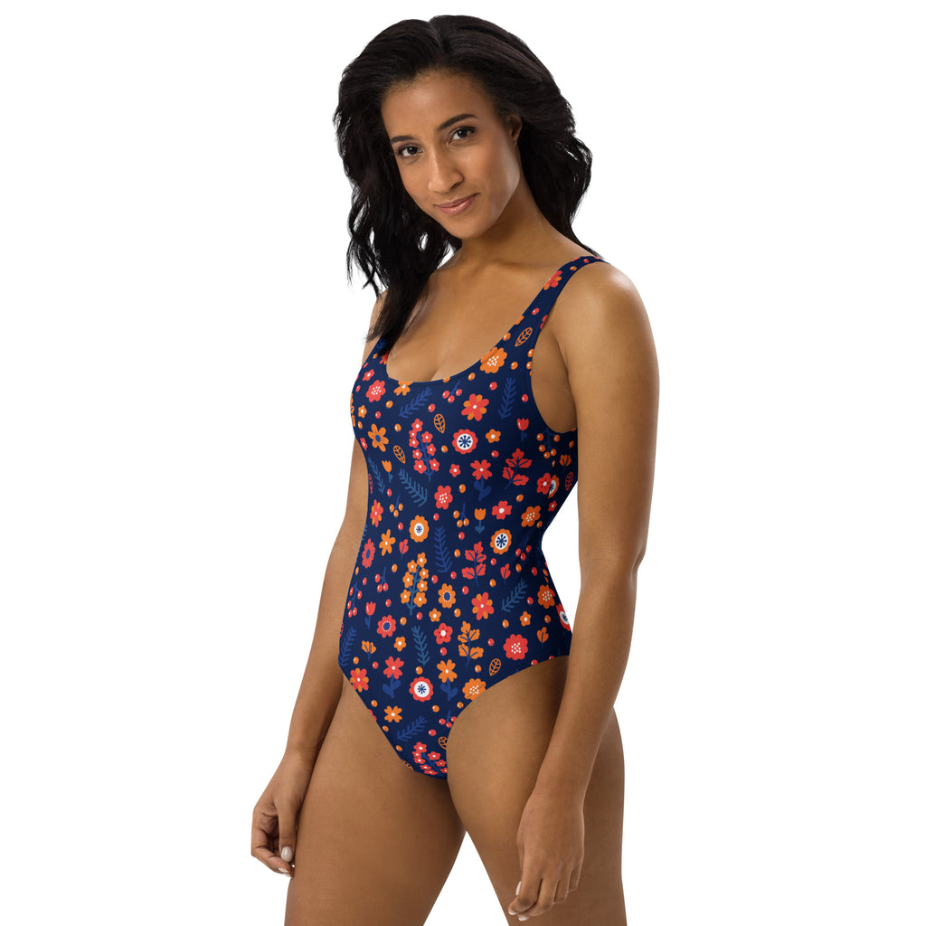 A navy blue women’s one-piece swimsuit with vibrant orange pink and red floral pattern and buttery soft fabric with UPF 50+