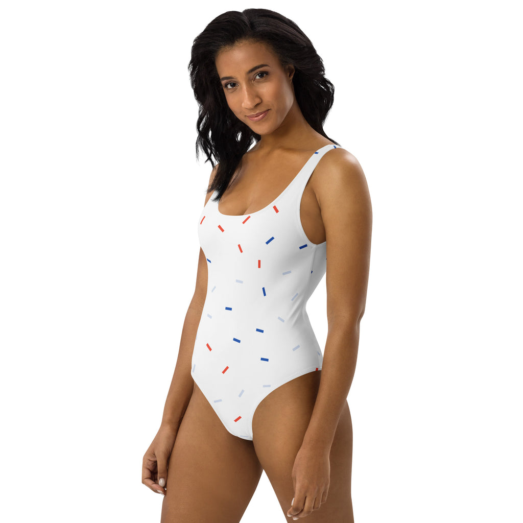 White one-piece swimsuit with playful red blue and gray sprinkles made from buttery soft fabric with upf 50+ protection