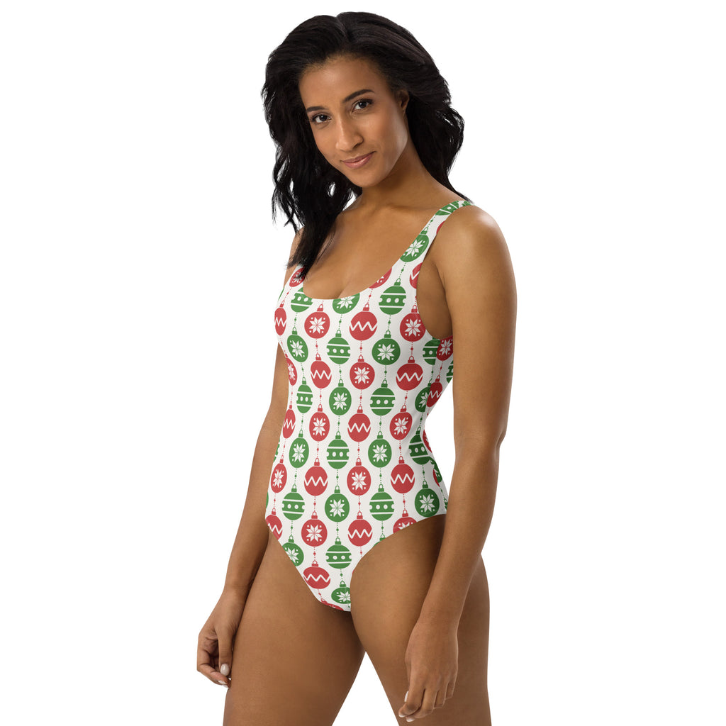A festive white one-piece swimsuit with a repeating red and green christmas ornament pattern and UPF 50+ protection