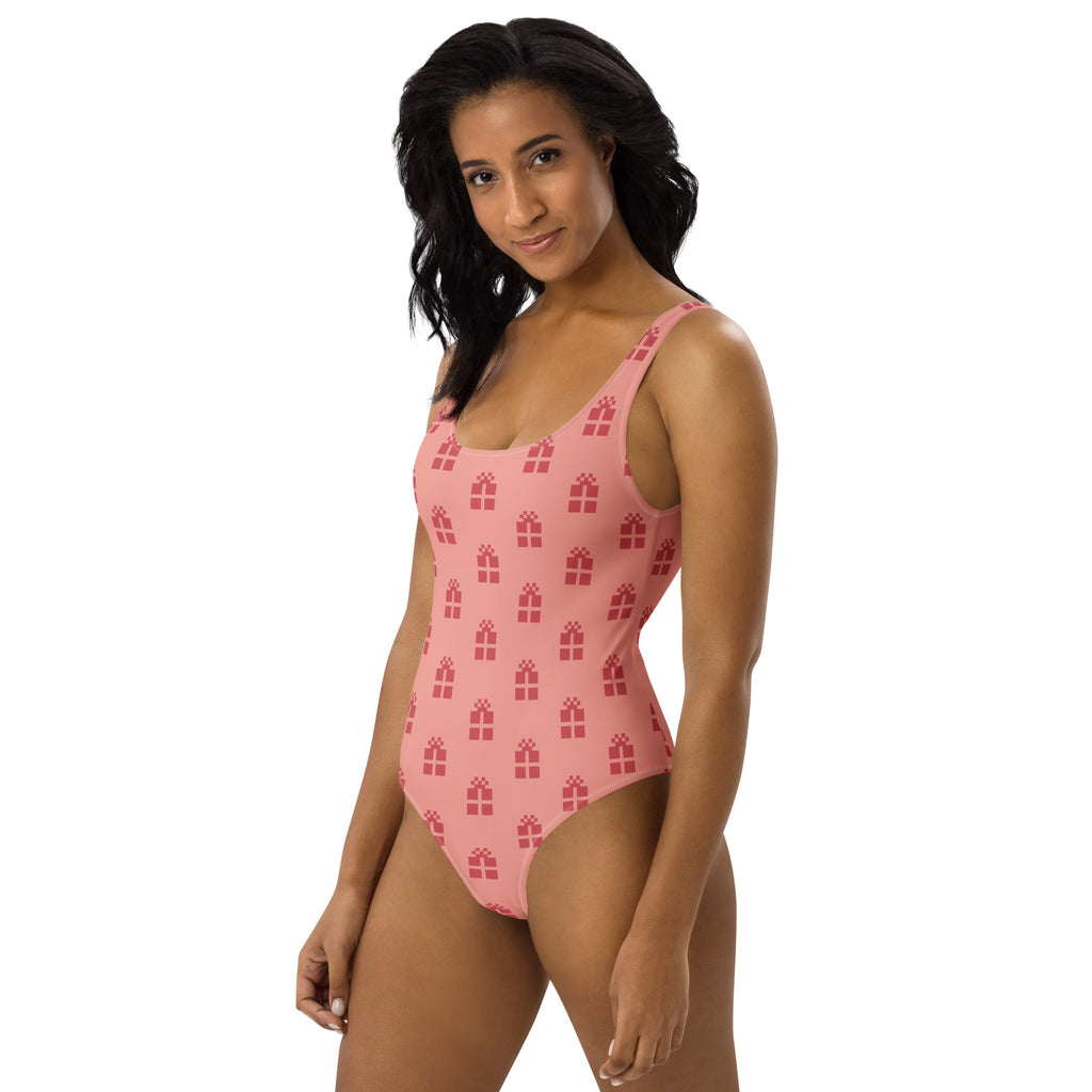 Women’s christmas gift buttery soft pink one-piece swimsuit with repeating red gift box pattern and upf 50+ protection
