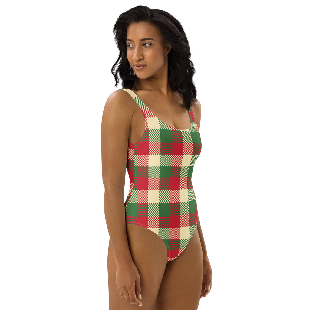 A woman wearing a women’s christmas plaid buttery soft swimsuit with upf 50 plus in red green and cream colors