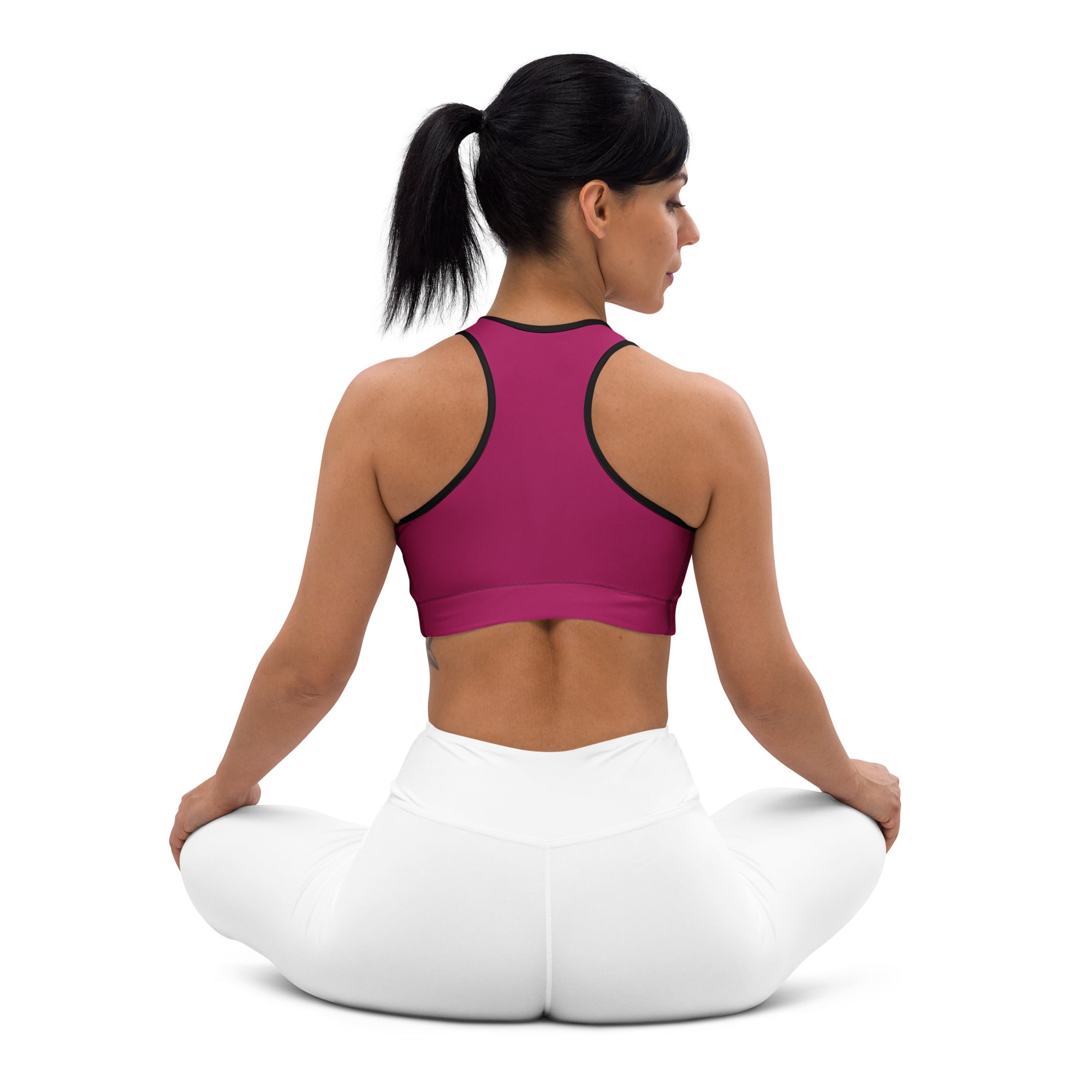 A magenta padded sports bra with black trim sits on a woman’s back showing its supportive quick-dry design